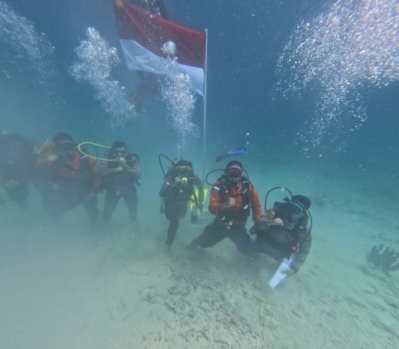 Anggota Polres Simeulue, Pos SAR, dan LSM Ecosystem Impact membentangkan Bendera Merah Putih di bawah laut perairan Simeulue, Aceh, Senin (17/8/2026).