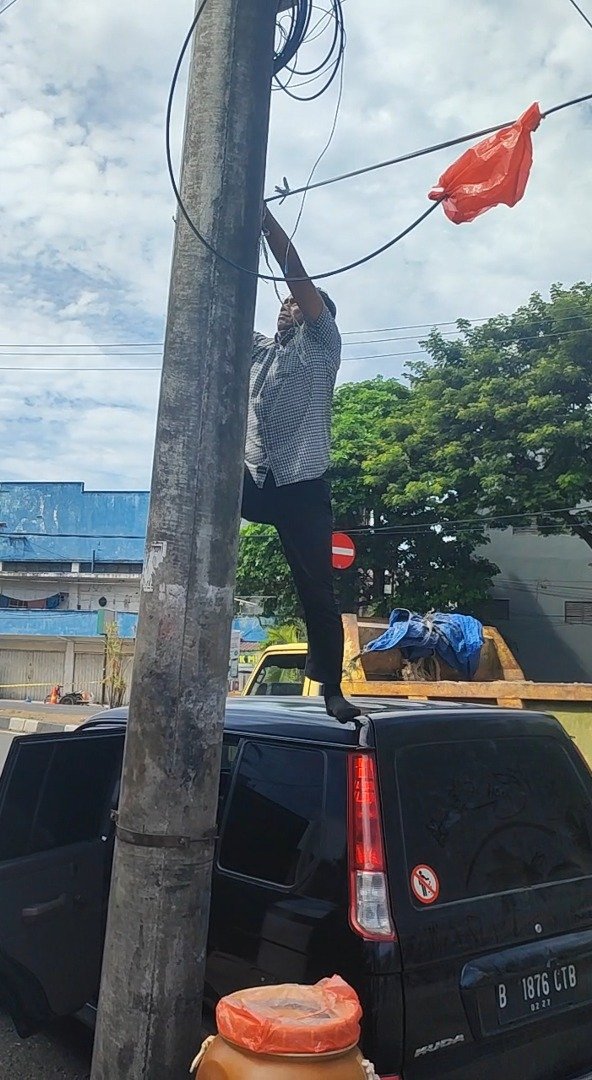 Aksi sigap Ipda Junaidi, Kanit II Satresnarkoba Polresta Banda Aceh, saat mengamankan kabel listrik yang membentang di Jl Cut Meutia Banda Aceh, Selasa (14/9/2026).