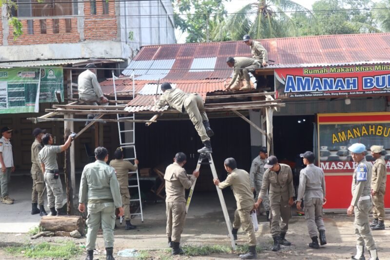 Petugas Satpol PP dan WH Aceh Besar membongkar bangunan liar di kawasan pintu masuk Bandara SIM, Kecamatan Blang Bintang, Aceh Besar, pada Kamis (22/10/2026). Foto: NA